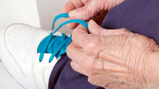 Senior woman tightening shoelaces on her footwear