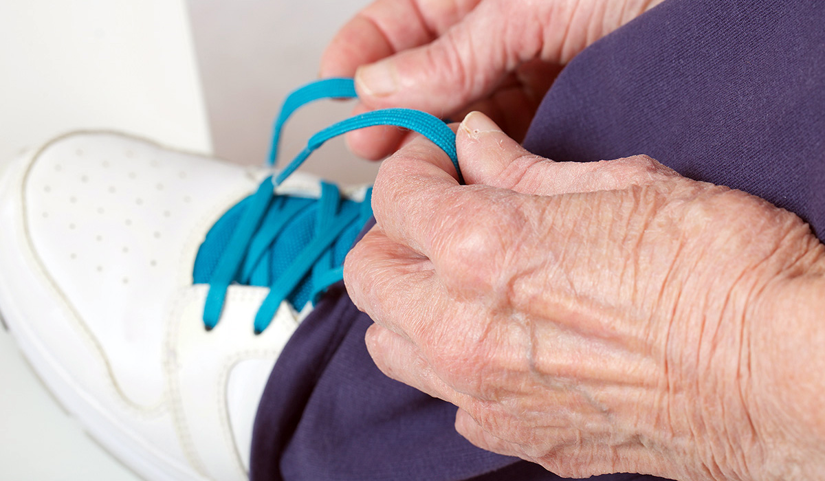Senior woman tightening shoelaces on her footwear
