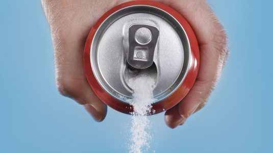 Cola can pouring out white sugar