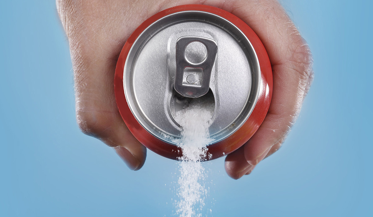 Cola can pouring out white sugar