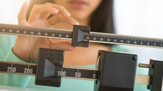 A woman adjusting balance weight scale