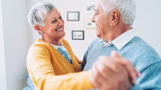 A happy senior couple dancing at home