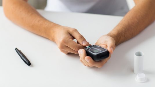 A man checking his blood sugar level by glucometer at home