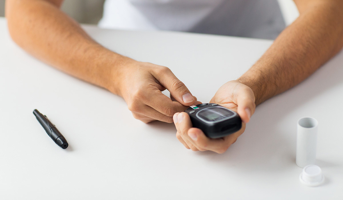 A man checking his blood sugar level by glucometer at home