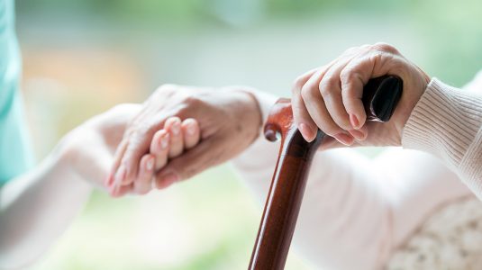 An elder person supported on a cane during rehabilitation