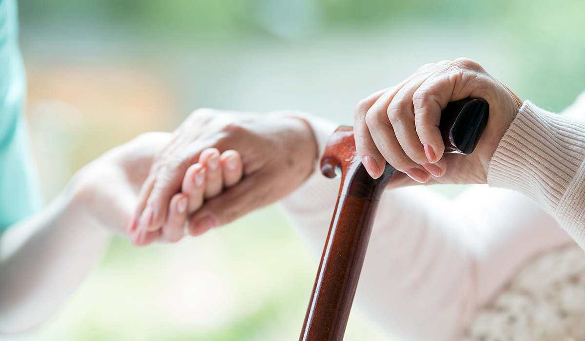 An elder person supported on a cane during rehabilitation