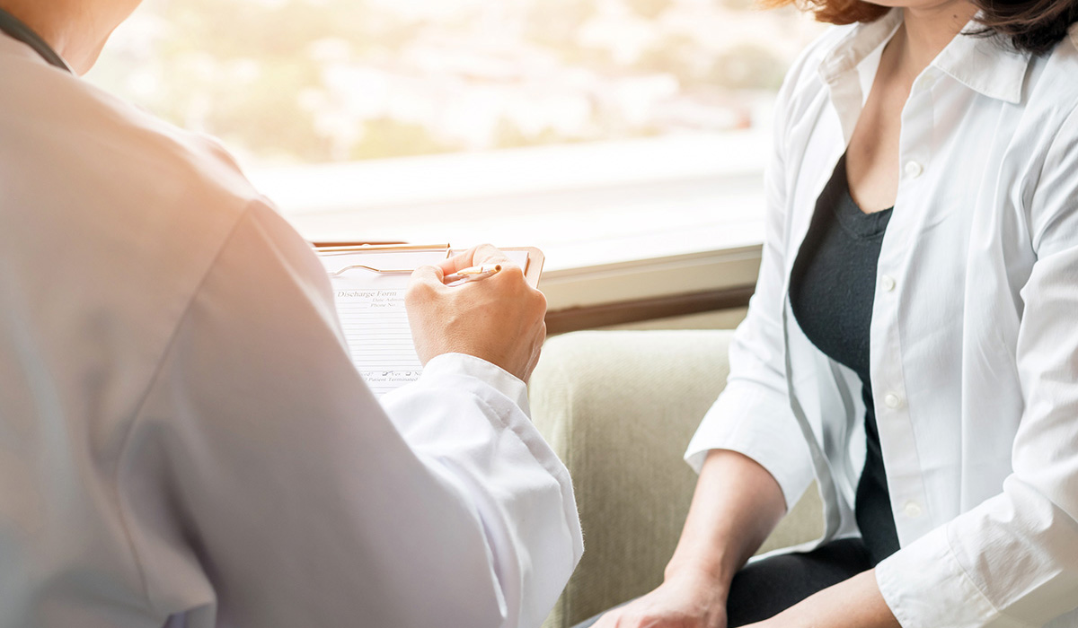 A doctor taking notes while talking to a patient