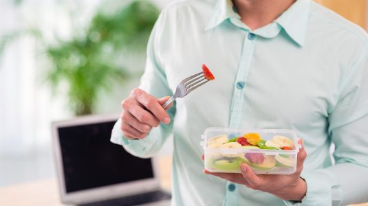 A man with a bowl of fruit salad at work