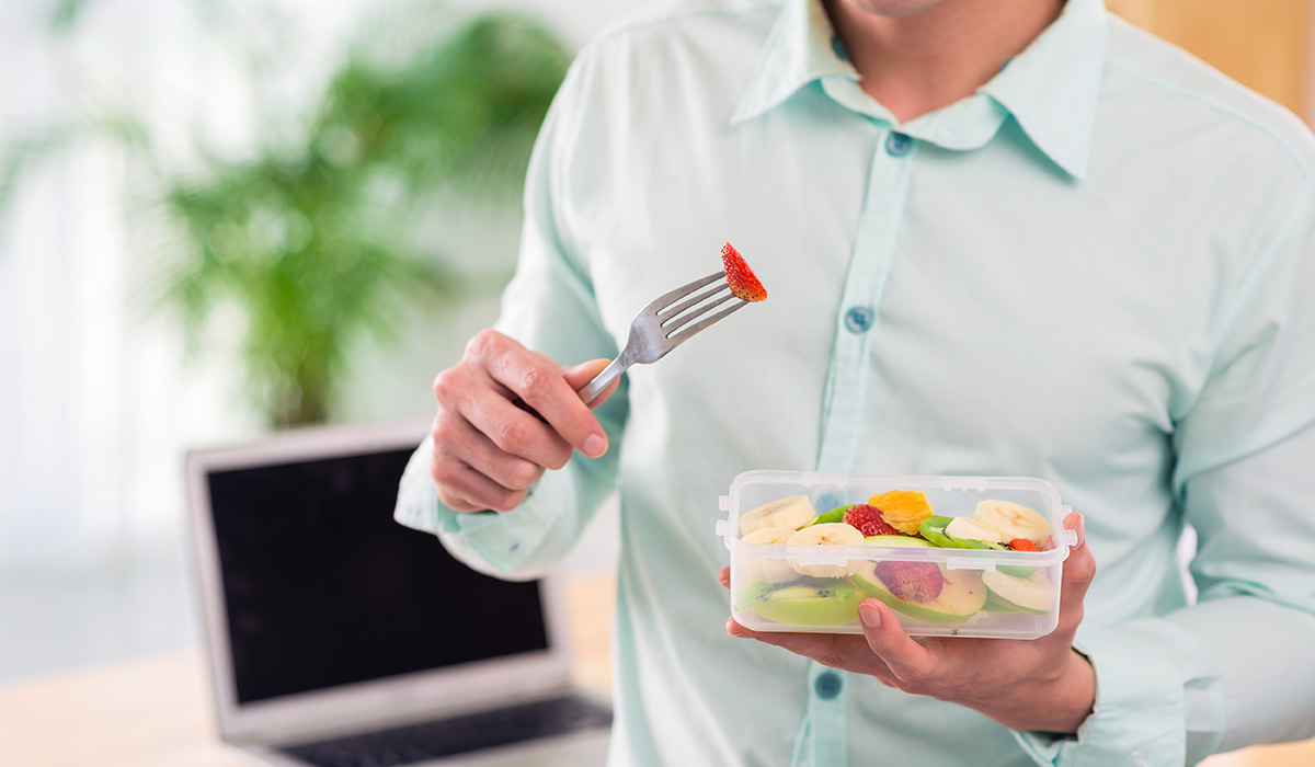 A man with a bowl of fruit salad at work