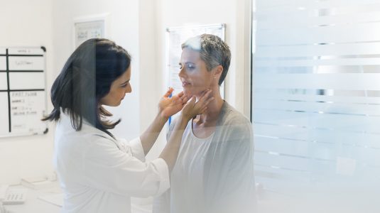A doctor examining her patient's thyroid glands