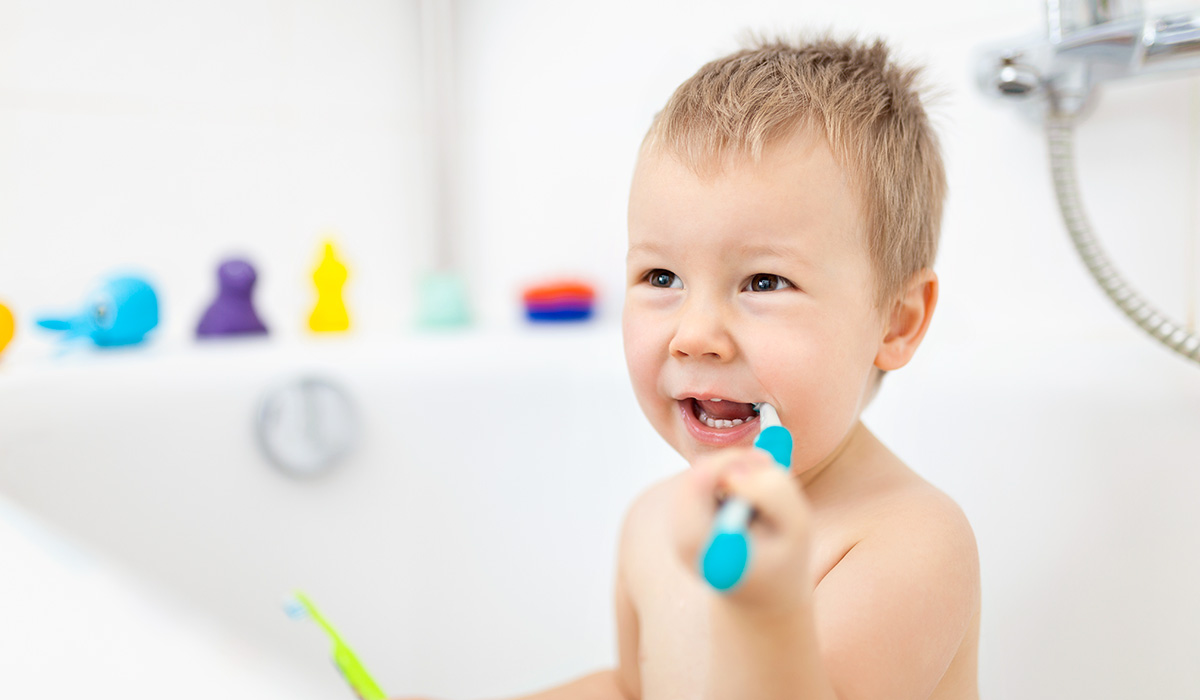Child learing how to brush his teeth in the bathroom