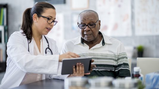 A doctor using a tablet computer to show her patient information