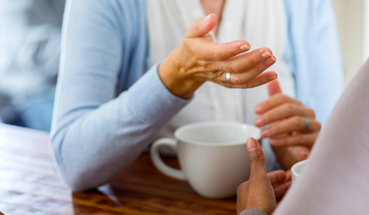 A senior having a coffee while chatting with someone