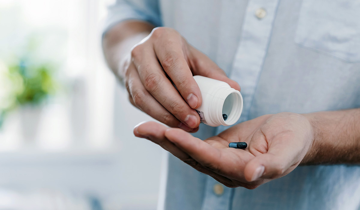 A person taking a pill from a bottle