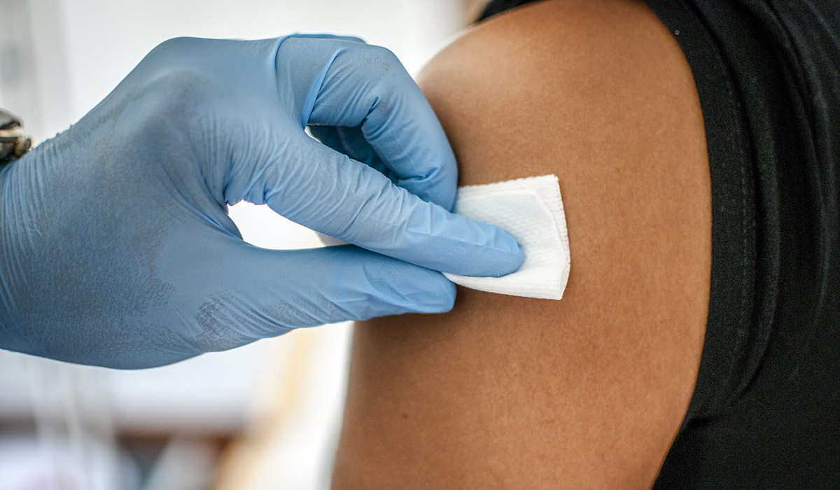 A doctor disinfects skin of patient before vaccination