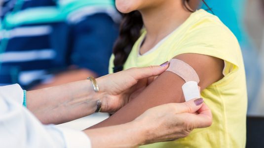 A person getting a flu shot and applying band aid