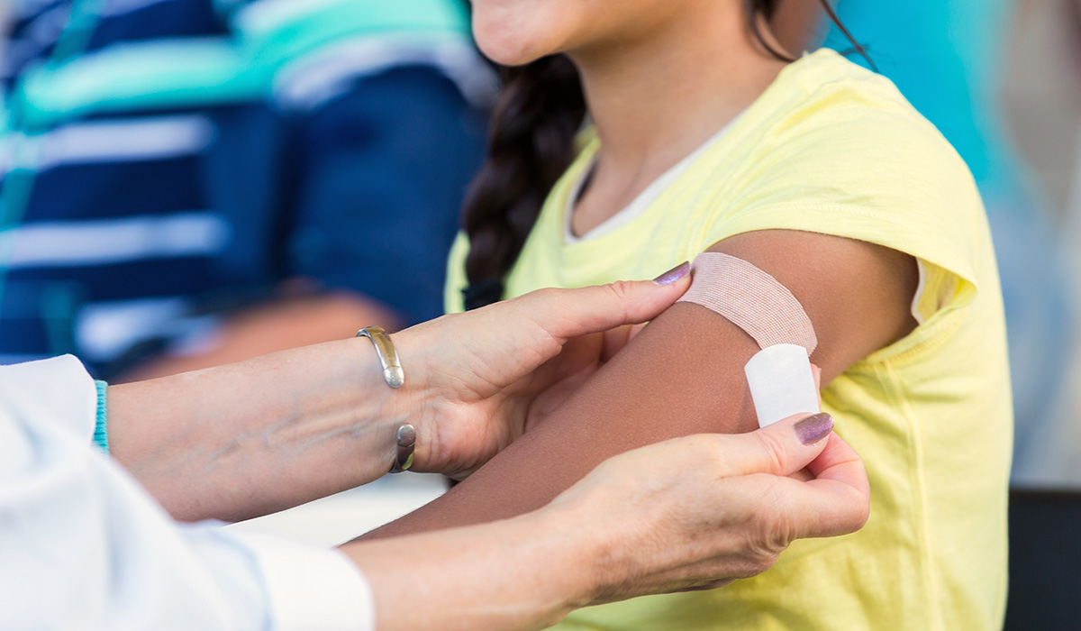 A person getting a flu shot and applying band aid