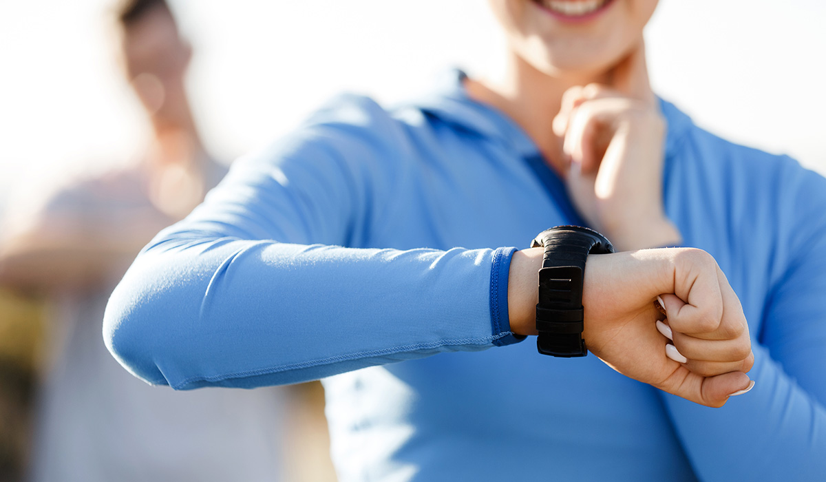 runner woman with heart rate monitor running on beach