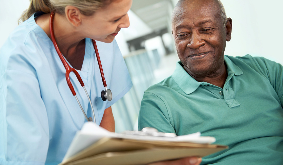 A nurse and an patient smiling as she shows him his test results