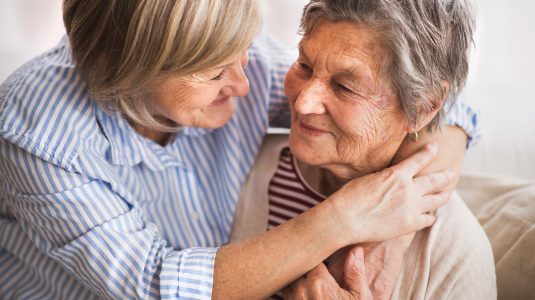 senior and her caregiver hugging