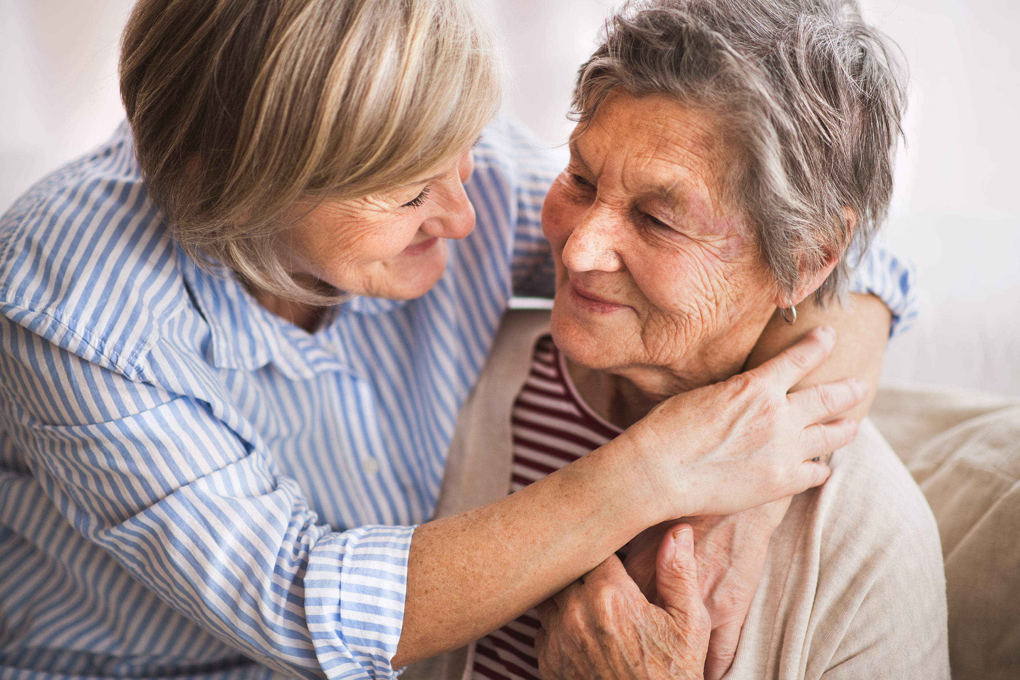 senior and her caregiver hugging