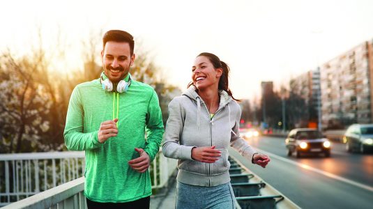 man and woman jogging outdoors in city
