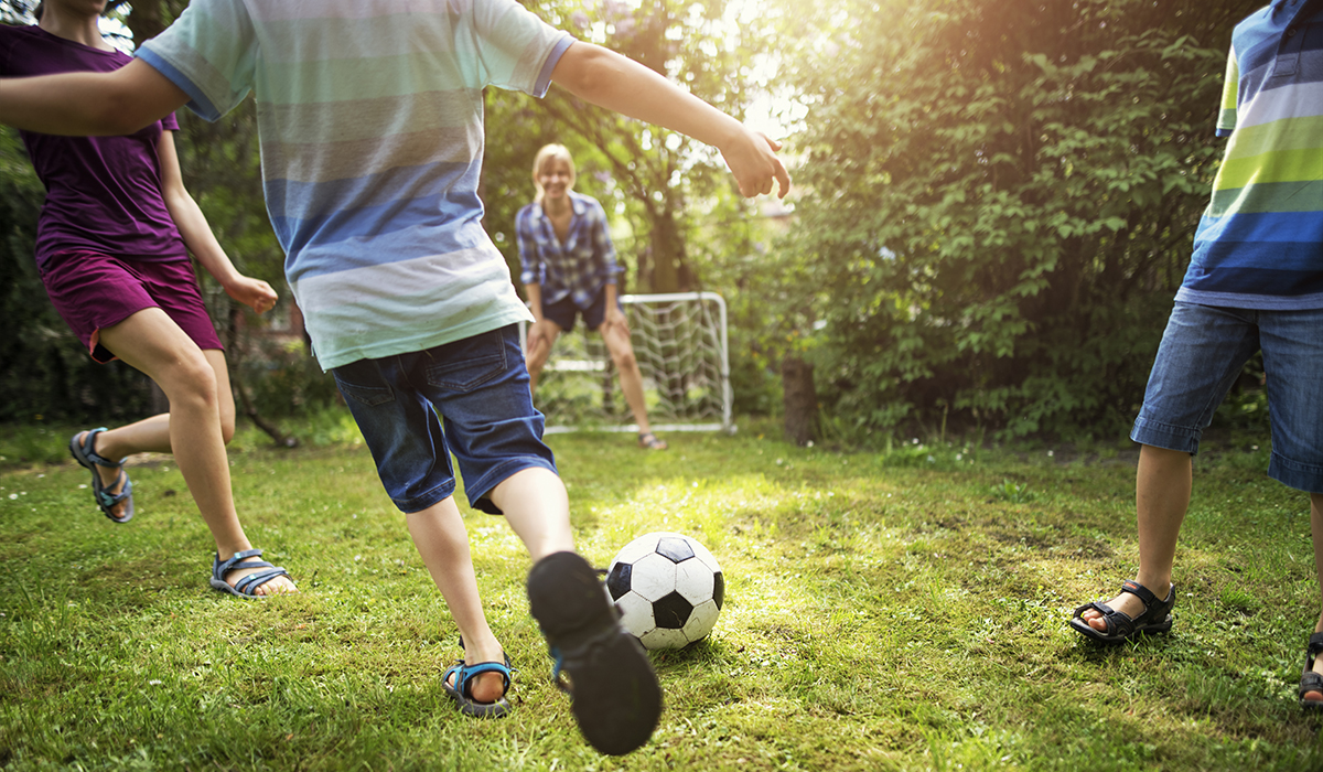 Mother and kids playing soccer in the garden