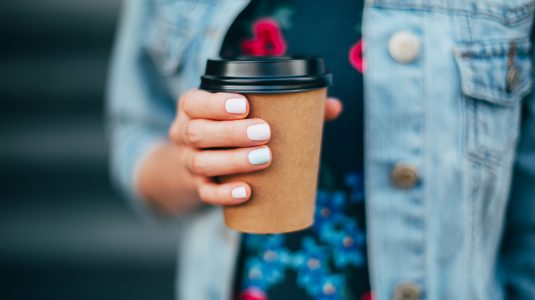 hand with paper cup of coffee take away