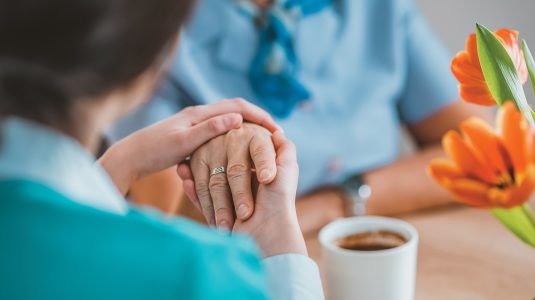 A person holding a senior's hand