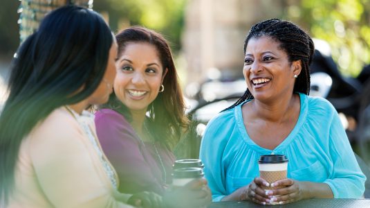 Three ladies having coffee and chatting outdoors