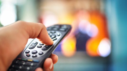 A hand holding a TV remote control