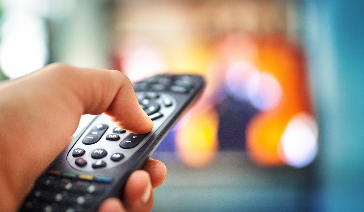 A hand holding a TV remote control