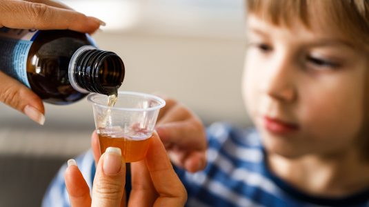 A child getting ready to have cough syrup