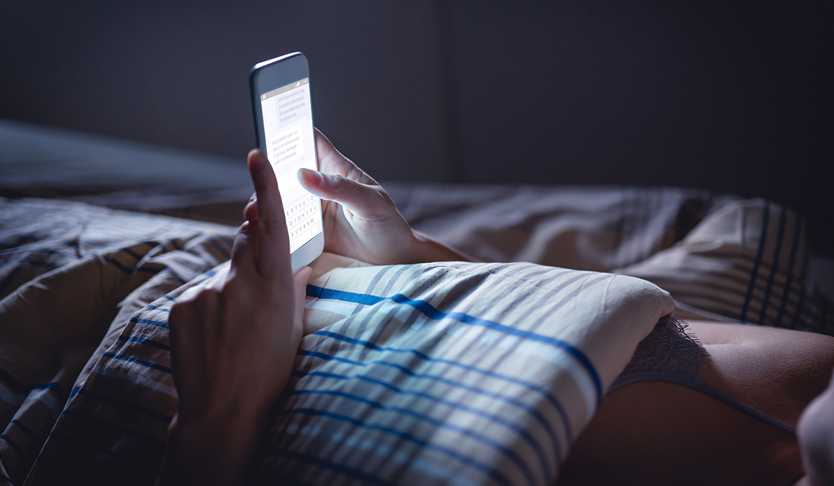 A person using a phone late night in bed