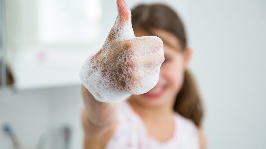 Little girl washing hands with water and soap