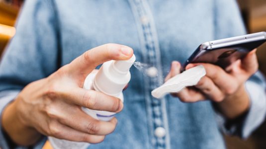 A person cleaning smartphone with antiseptic