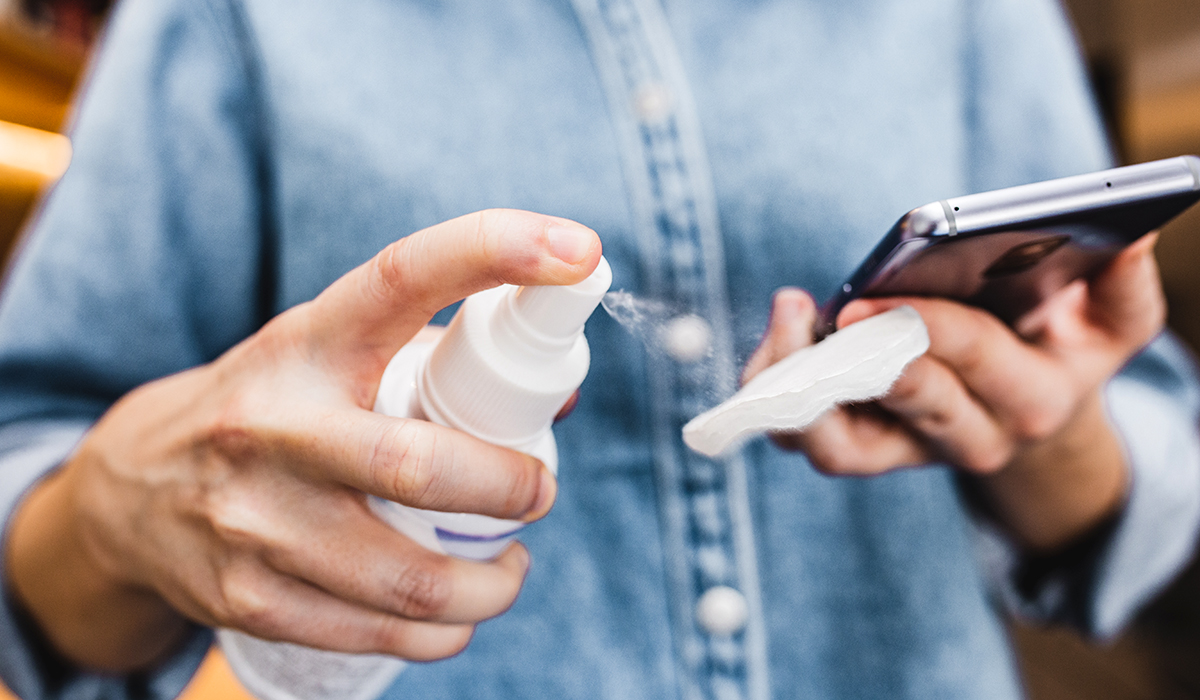 A person cleaning smartphone with antiseptic
