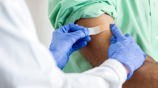 Pharmacist places a bandaid on a customer's arm after immunization.jpg