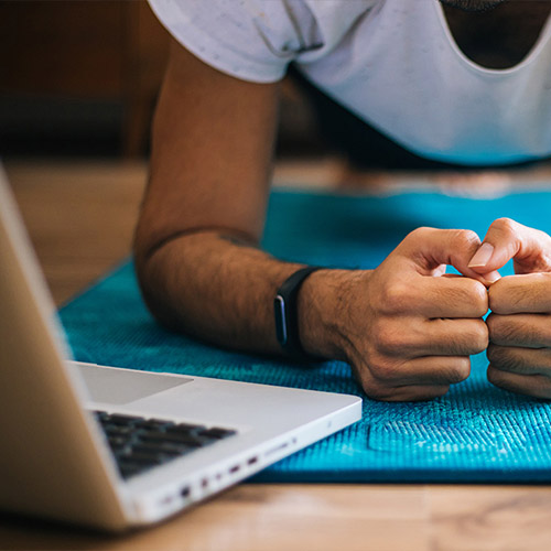 A person working out at home with a laptop