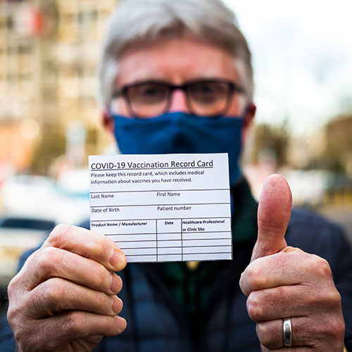 A person holding out his covid vaccination card